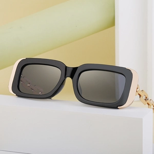 Detailed shot of black rectangular sunglasses featuring gold chain-link temple arms