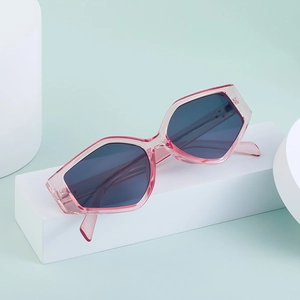 Detail view of pink polygonal geometric sunglasses with grey lenses on white props