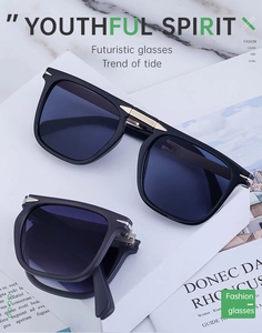 Detail view of foldable black sunglasses with dark blue lenses on a white display stand