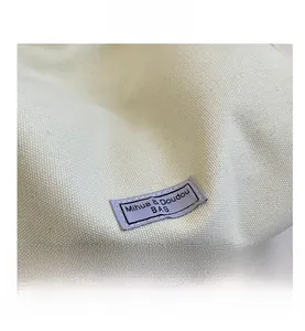 Detailed macro view of cream canvas material with purple rectangular Mihua & Doudou fabric label