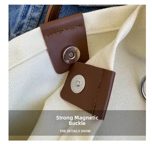 Detail view of strong magnetic snap closure and leather patch on canvas tote bag