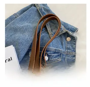 Detail of brown leather strap with silver metal chain links on denim background
