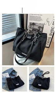 Detail of minimalist black canvas tote bag with metal chain strap and white label