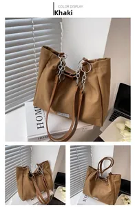 Detail of khaki canvas tote with thick metal chain and leather strap on a desk