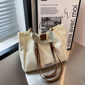 Retro cream canvas tote bag with brown PU straps and metal chain in warm cinematic lighting