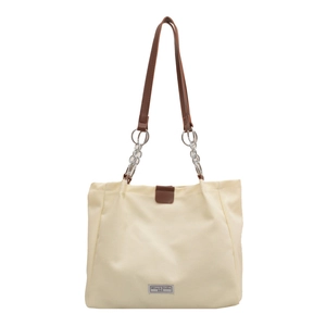Minimalist beige canvas tote bag with brown leather handles and chic chain details