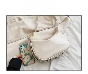 Comparaison de taille d'un sac à bandoulière demi-lune blanc cassé avec un téléphone