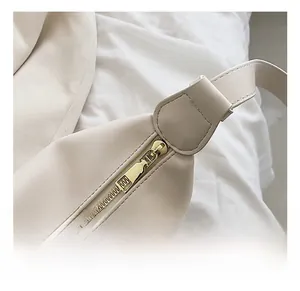 Détail macro de la fermeture éclair dorée et du cuir crème lisse du sac à main chic