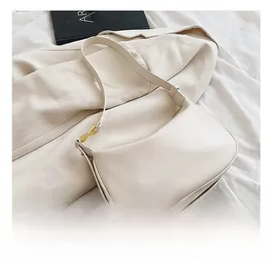 Détail d'un sac hobo crème en similicuir avec boucles dorées en X et fine bandoulière