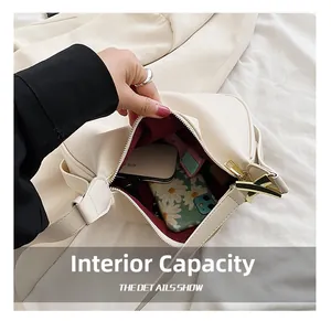 Capacité interne du sac à bandoulière crème avec téléphone et cosmétiques sur tissu blanc