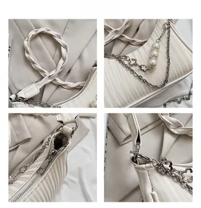 Détails d'un sac à main plissé crème avec chaînes de perles et breloques fleuries