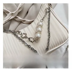 Détail du sac à bandoulière crème avec texture plissée et chaîne à grandes perles