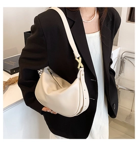 Vue détaillée du sac demi-lune crème avec ferrures métalliques dorées en forme de X