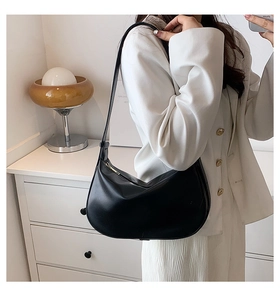 Détail d'un sac hobo noir en cuir synthétique lisse avec une fermeture éclair dorée