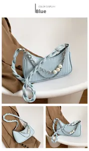 Détail d'un sac à épaule plissé bleu clair avec bandoulière tressée et perles