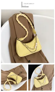 Détail du sac baguette jaune avec breloque perle et bandoulière en cuir tressé