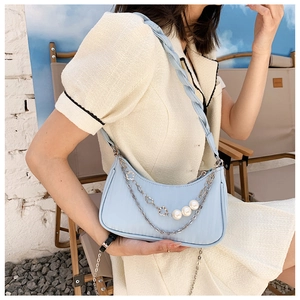 Gros plan d'un sac hobo en nylon bleu clair avec bandoulière tissée et chaînes à fleurs