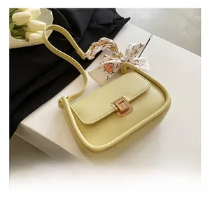 Detail of light green leather crossbody bag with elegant silk scarf on shoulder strap
