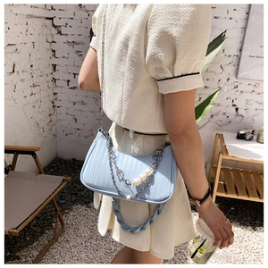 Détail du sac bandoulière bleu clair avec texture rayée et bandoulière en perles