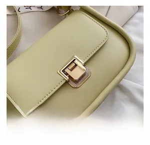 Close-up of golden hardware lock on light green leather crossbody square bag