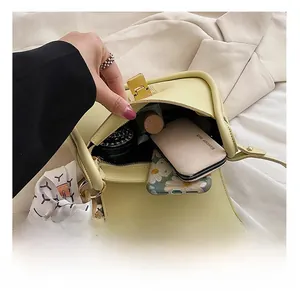 Detail showing internal capacity of the cream faux leather crossbody bag with items