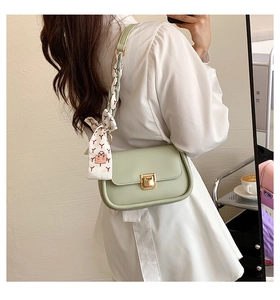 Detail of light green square bag featuring a gold buckle and floral scarf handle