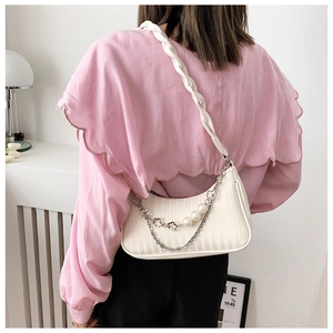 Détail du sac à bandoulière plissé crème avec breloques perles et bandoulière tissée