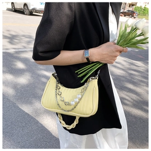 Gros plan d'un sac à bandoulière jaune clair plissé avec perles et chaîne argentée