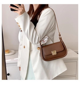 Brown leather crossbody bag with gold buckle worn with a white blazer in a mirror selfie