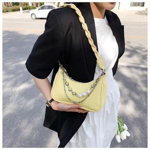 Détail du sac plissé jaune avec chaîne argentée et accents de perles blanches