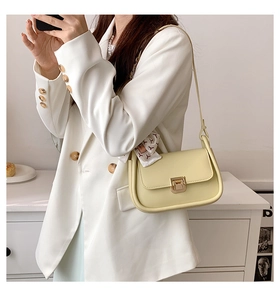 Detail of light yellow crossbody bag with gold twist lock and decorative silk scarf strap