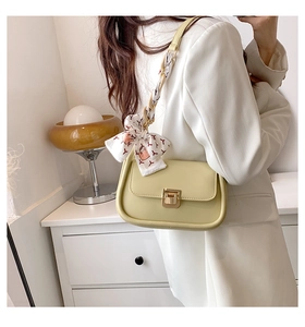 Close-up of yellow rectangular shoulder bag with golden lock and decorative silk scarf