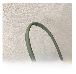Close-up of green leather tote bag featuring a round handle and decorative ribbon detail