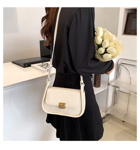 Detailed view of a creamy white minimalist crossbody bag with elegant gold buckle hardware