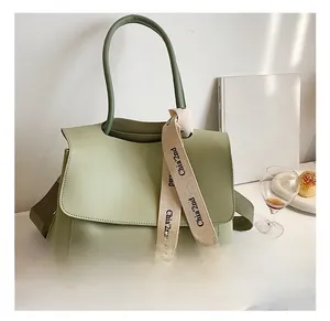 Macro shot of pale green leather tote bag featuring a decorative logo ribbon and wide strap