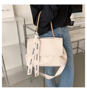 Close-up of cream tote bag featuring a decorative printed ribbon handle and chic urban style