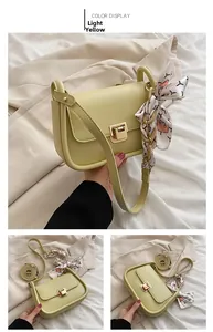 Detailed view of light yellow crossbody bag with gold buckle and floral silk scarf strap