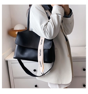 Detail showing high-quality black leather tote bag with a custom lettered wide shoulder strap