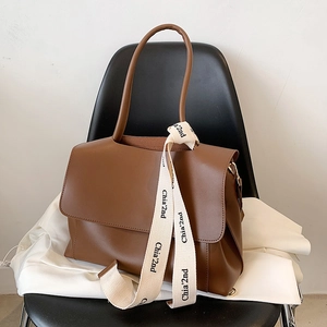 Brown leather large tote bag with decorative brand ribbon and elegant flap closure