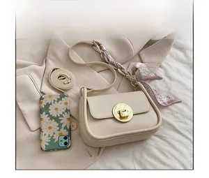Detail of a beige flap handbag with gold round lock and floral silk scarf accessory