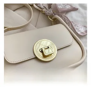 Detail of beige square bag with a large gold round lock and floral silk scarf accessory