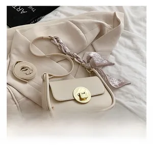Close-up of beige shoulder bag with gold metal buckle and floral scarf detail