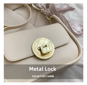 Close-up of golden hardware lock and floral scarf detail on beige crossbody bag