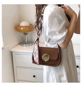 Close-up of brown vintage shoulder bag with golden lock and floral silk scarf detail