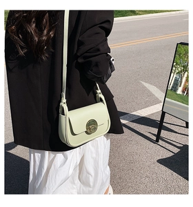 Close-up of mint green leather shoulder bag featuring a gold round magnetic buckle