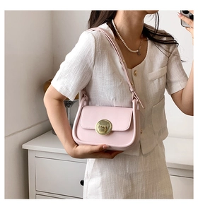 Detail of light pink crossbody square bag with golden buckle on a fashion model