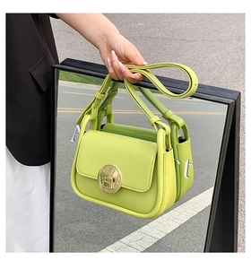 Detail of lime green leather handbag with gold metal lock against a mirror reflection