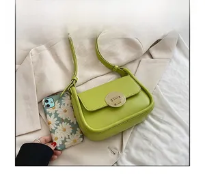Top view of avocado green leather crossbody bag with metal buckle next to a smartphone