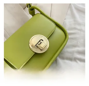 Close-up of golden circular metal twist lock on a sage green faux leather shoulder bag