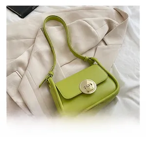 Detail of neon green leather bag with gold metal twist lock on beige blazer jacket